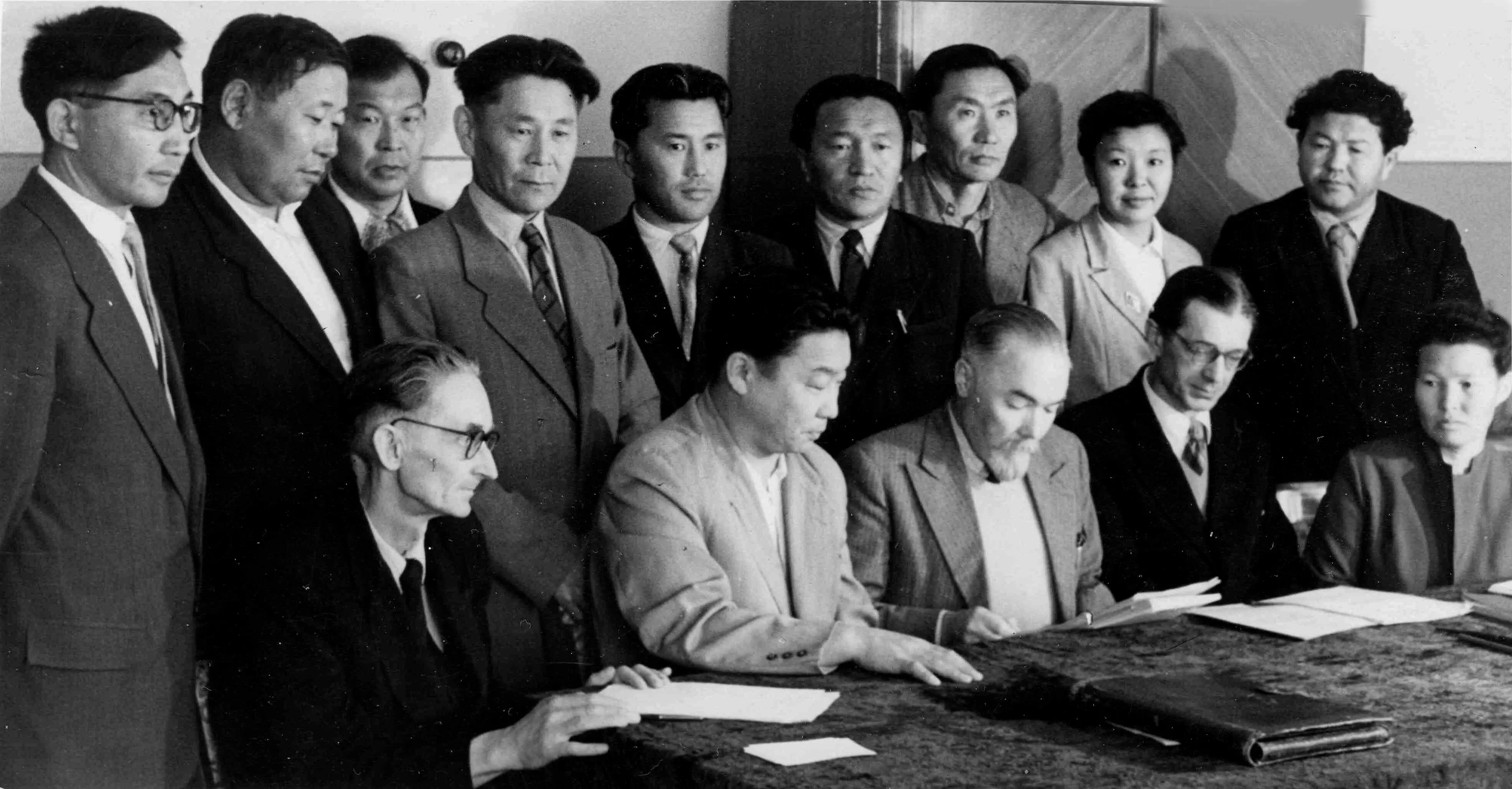 Стоят слева направо: Г. Л. Санжиев, Ц. Б. Цыдендамбаев, А. К. Зугеев, Б
                     . Д. Цыбиков, П. Б. Балданжапов, Р. Е. Пубаев, Б. Д. Дандарон, Е. В.
                     Мальцева, П. И. Хадалов; сидят: Б. В. Семичов, Д. Д. Лубсанов, Ю. Н. Рерих,
                     Г. Н. Румянцев, К. М. Герасимова. Улан-Удэ, 1959 г.